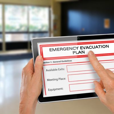 Hands with Computer Tablet and Emergency Evacuation Plan
